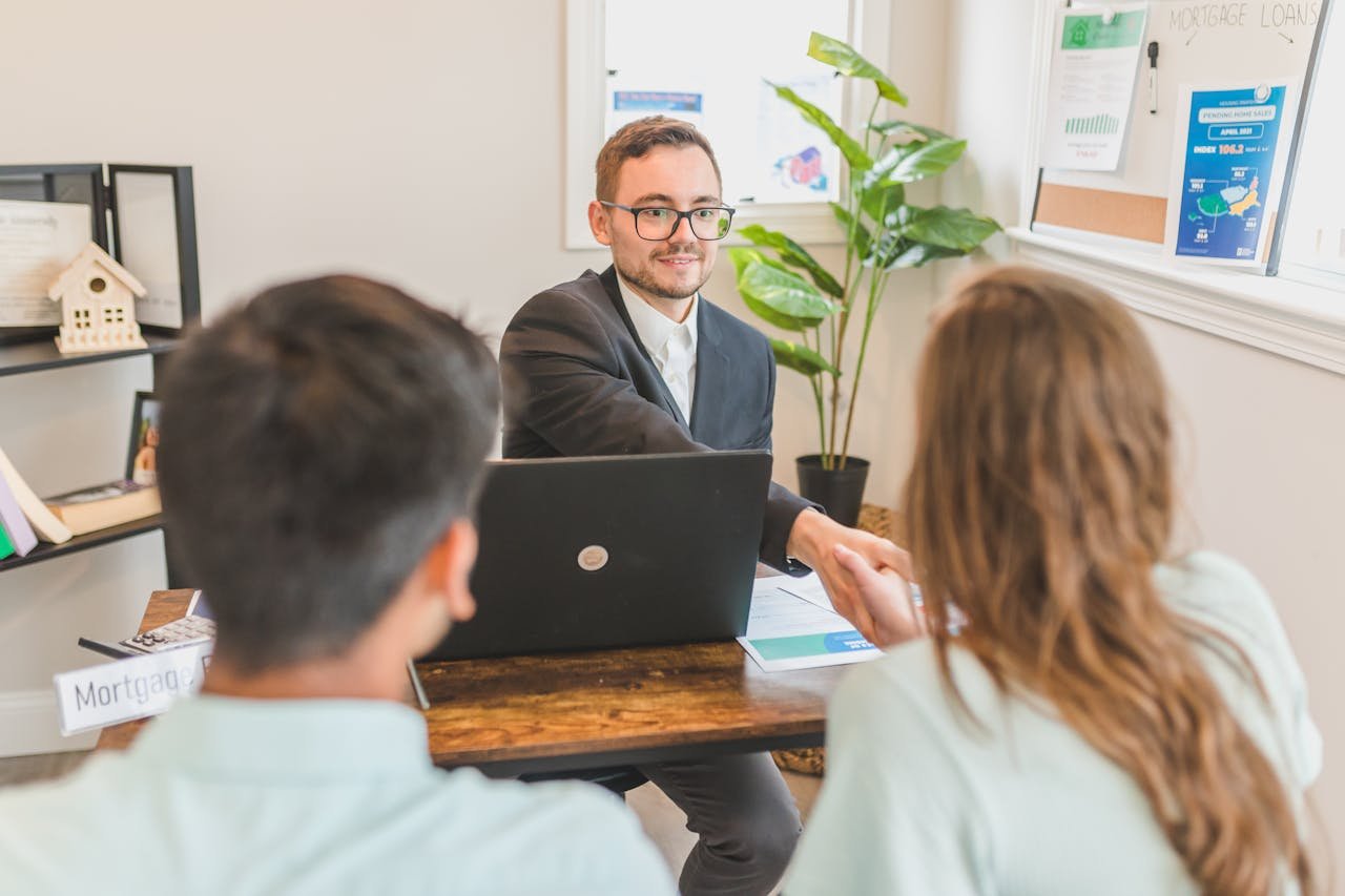 A mortgage broker meeting clients in an office, discussing agreements and loans.